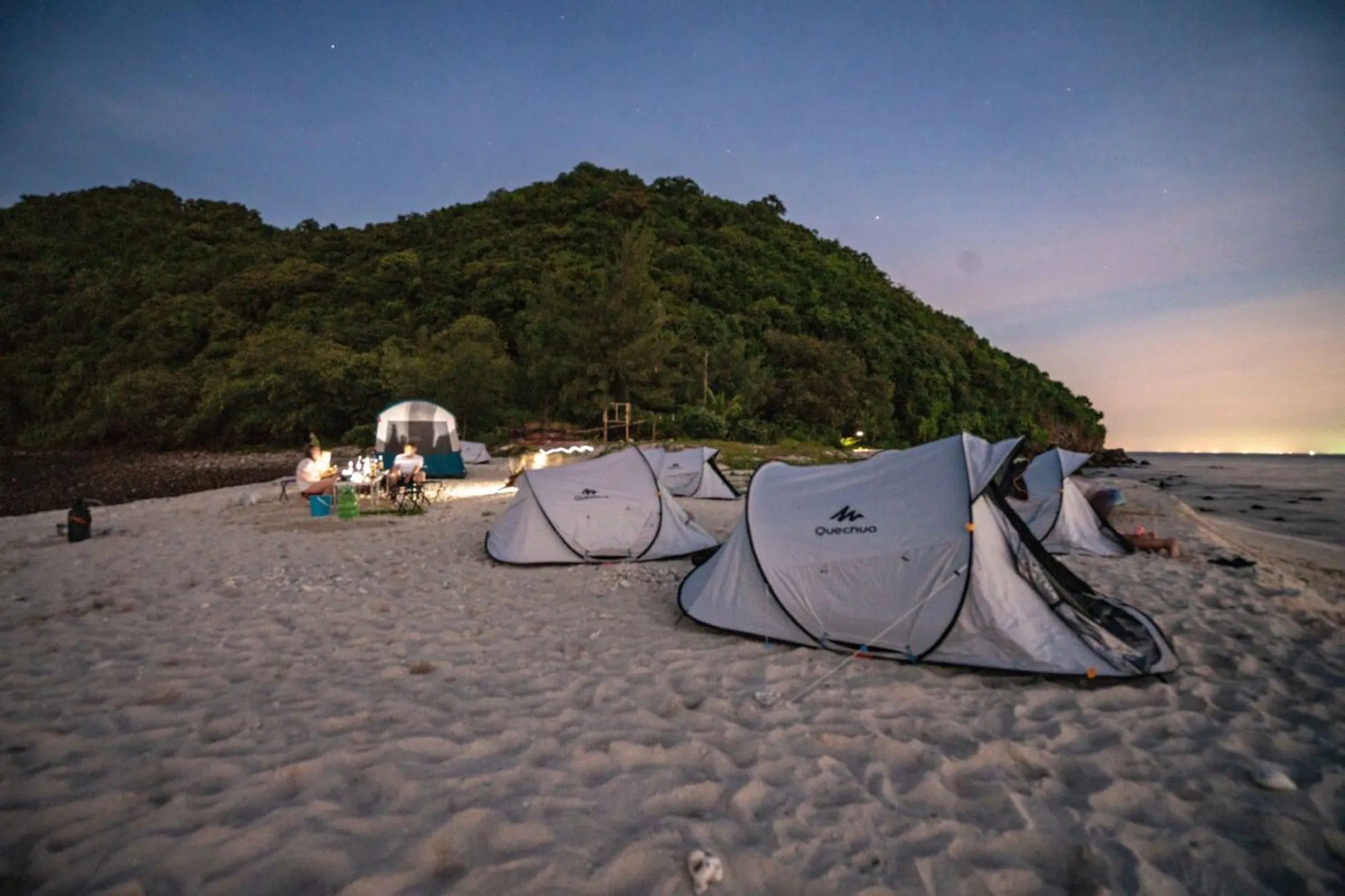 Tents glowing at twilight on the beach of Koh Kye, Thailand.